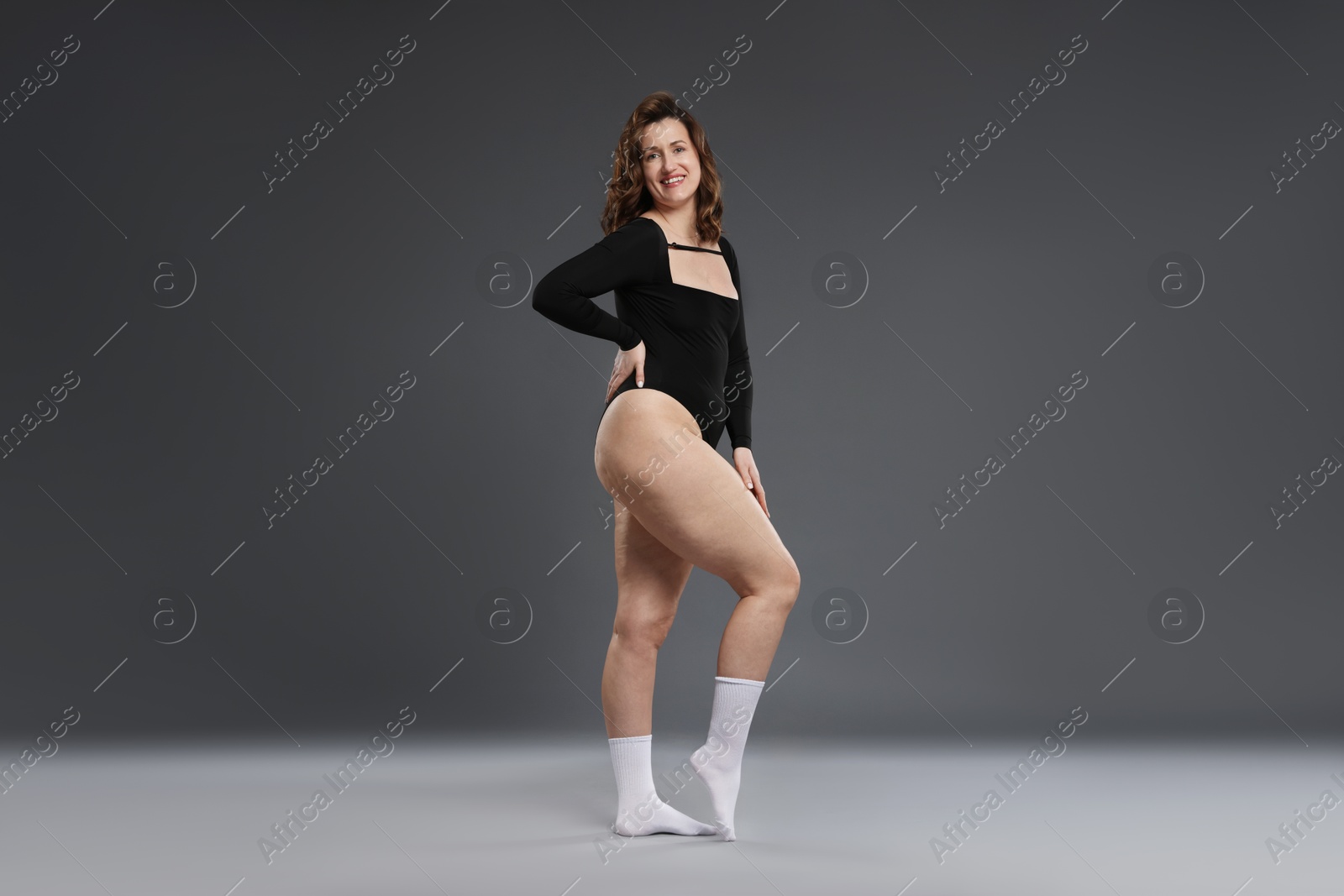 Photo of Beautiful woman in bodysuit on dark grey background. Cellulite problem