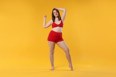 Photo of Woman in red underwear on orange background. Cellulite problem