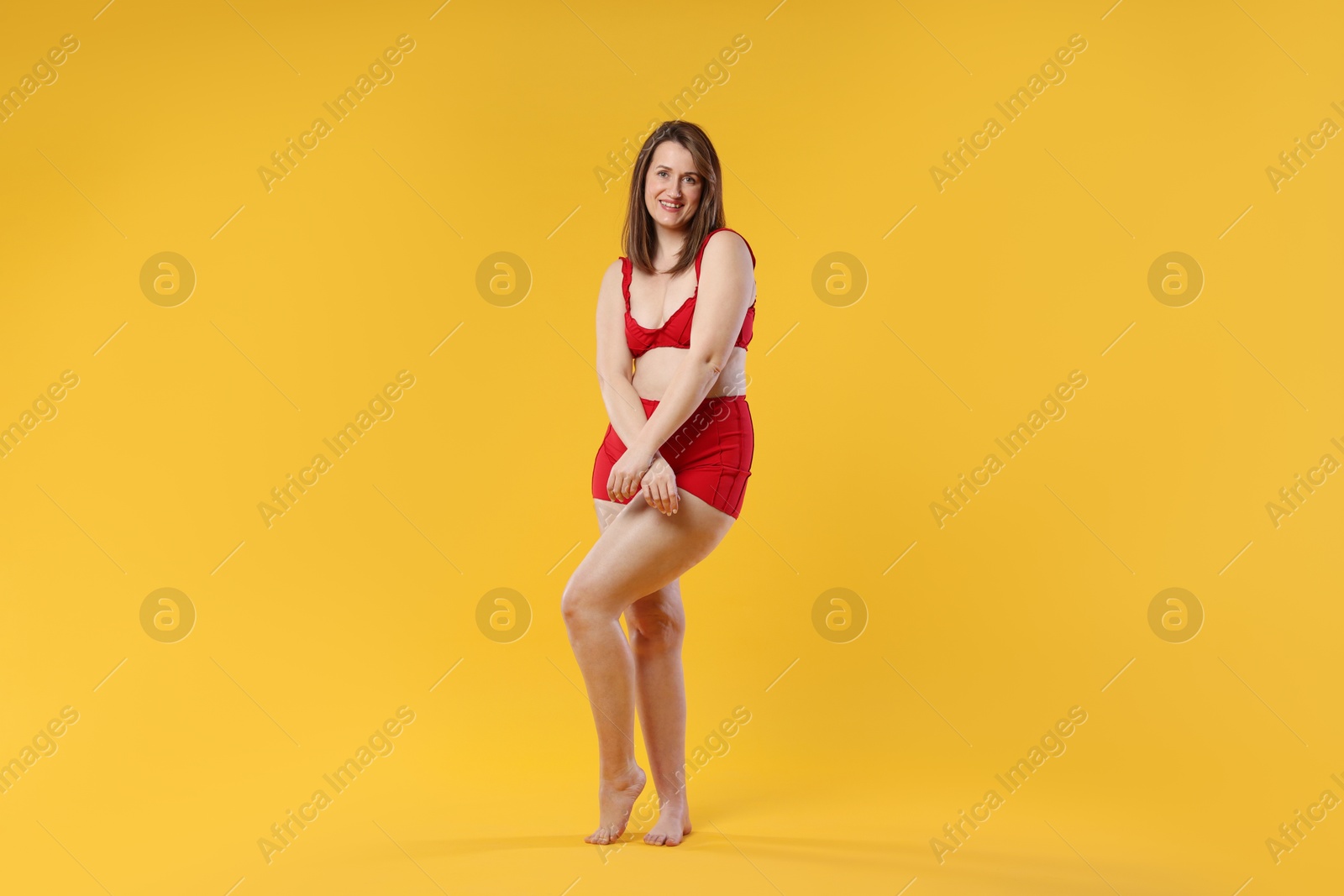 Photo of Woman in red underwear on orange background. Cellulite problem