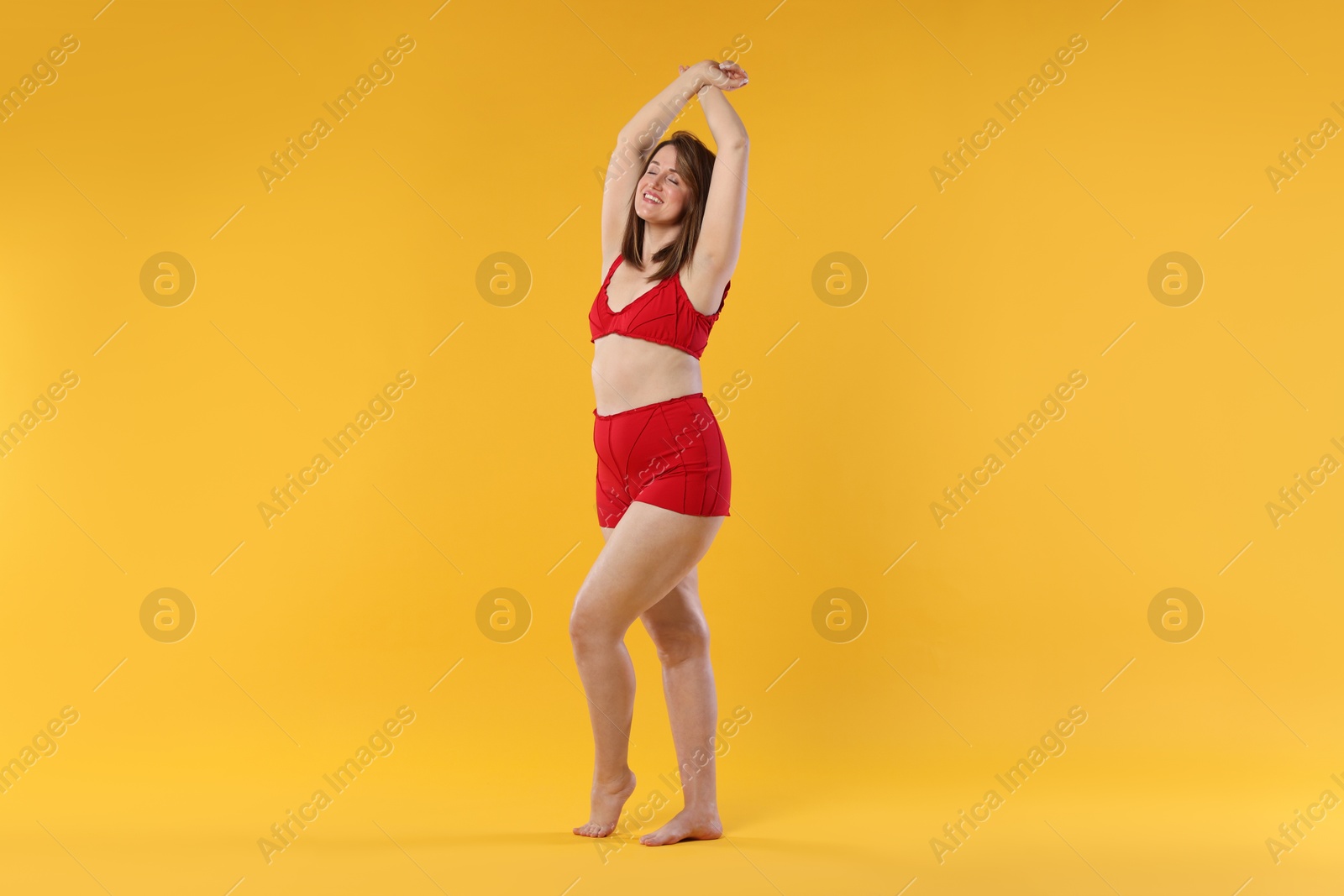 Photo of Woman in red underwear on orange background. Cellulite problem