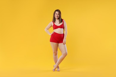 Photo of Woman in red underwear on orange background. Cellulite problem