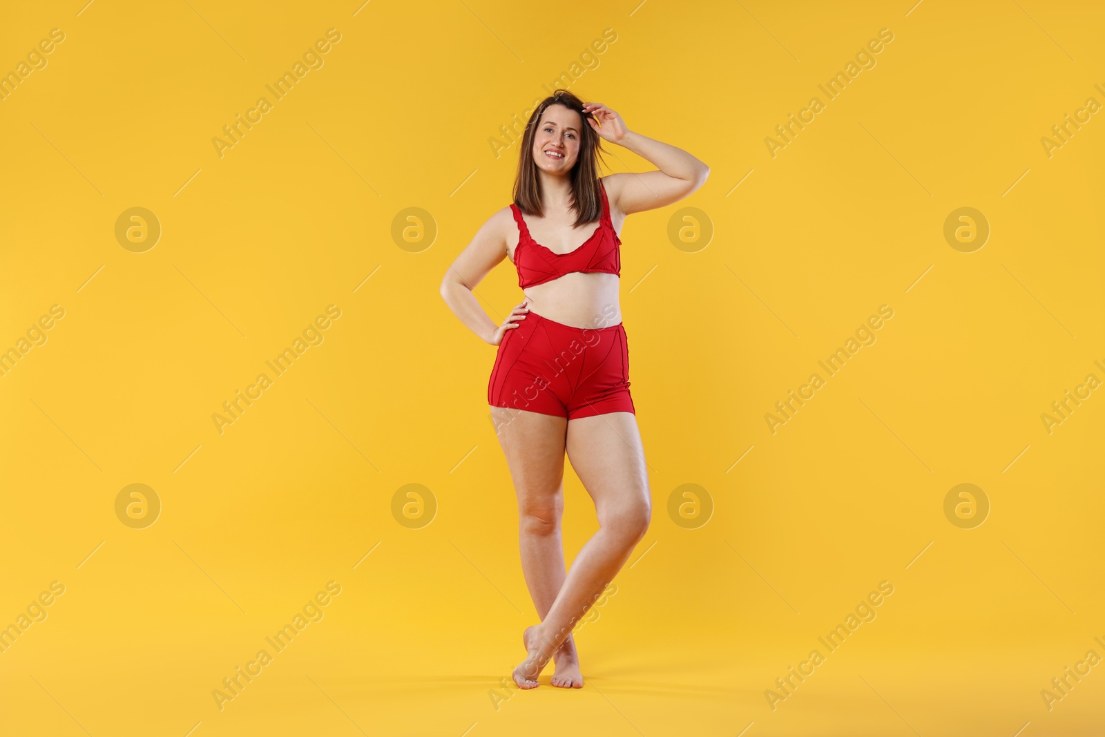 Photo of Woman in red underwear on orange background. Cellulite problem