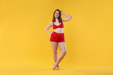 Photo of Woman in red underwear on orange background. Cellulite problem