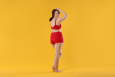 Photo of Woman in red underwear on orange background. Cellulite problem