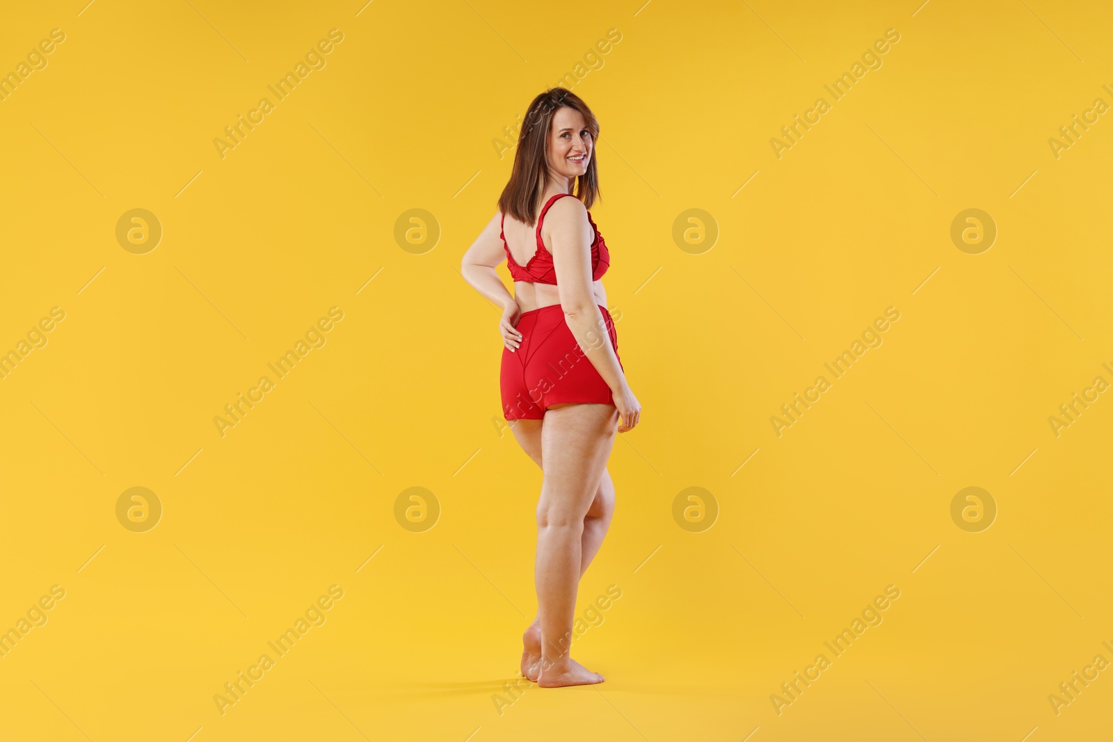 Photo of Woman in red underwear on orange background. Cellulite problem