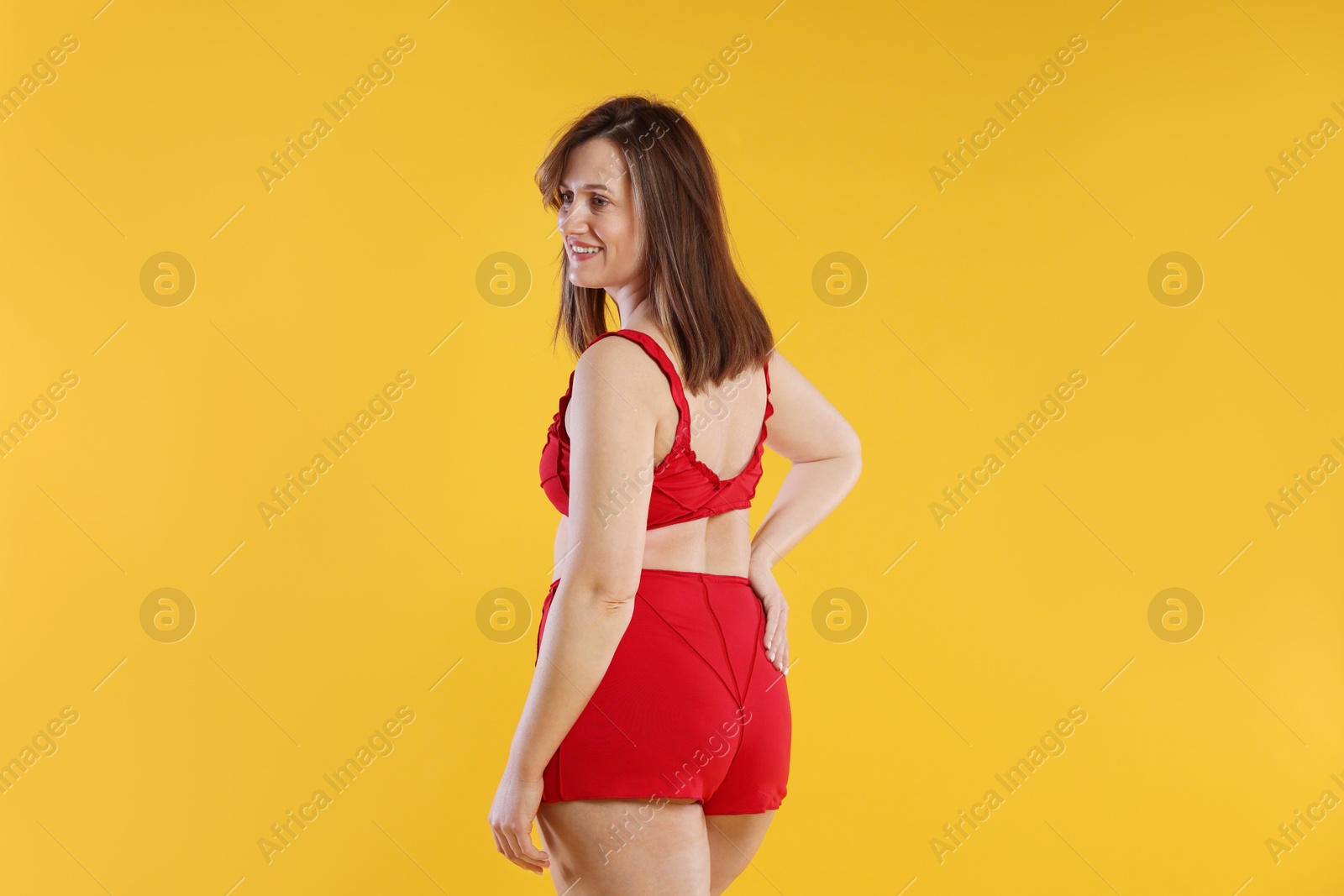 Photo of Woman in red underwear on orange background. Cellulite problem