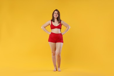 Photo of Woman in red underwear on orange background. Cellulite problem