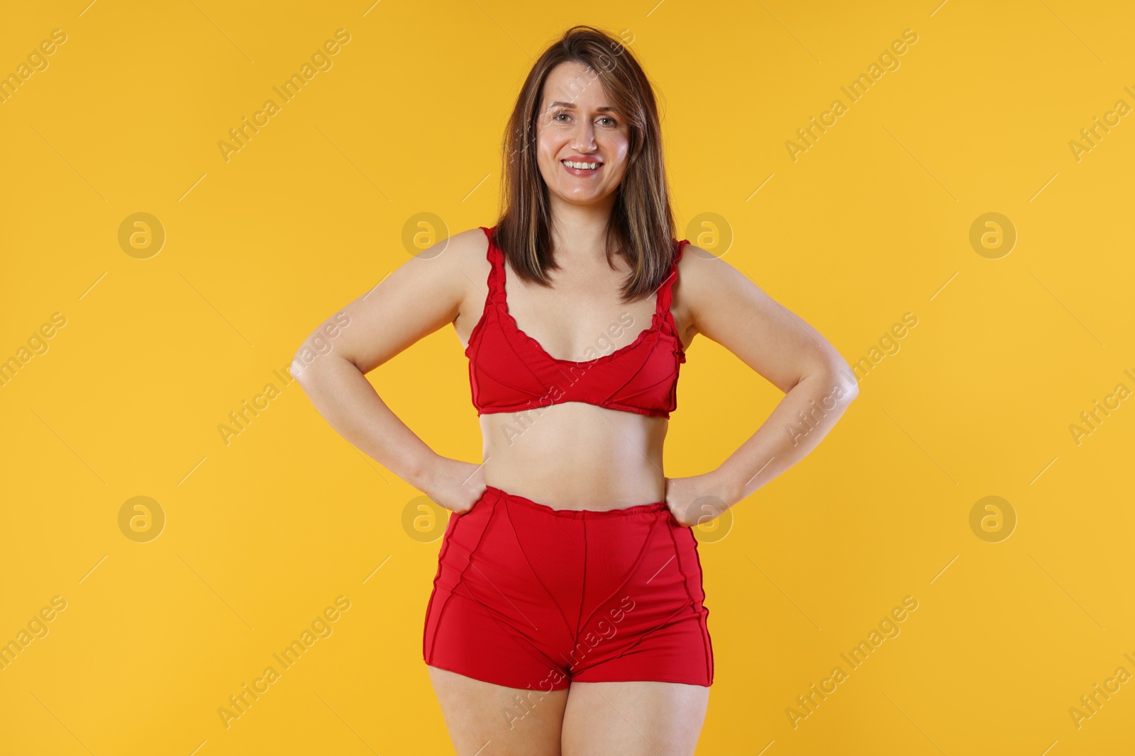 Photo of Woman in red underwear on orange background. Cellulite problem