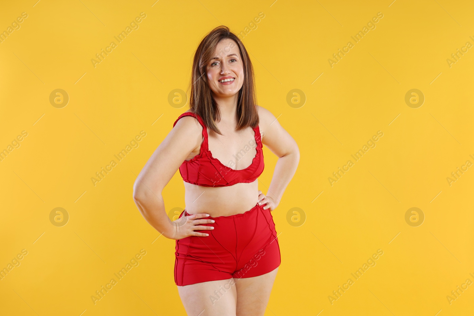 Photo of Woman in red underwear on orange background. Cellulite problem