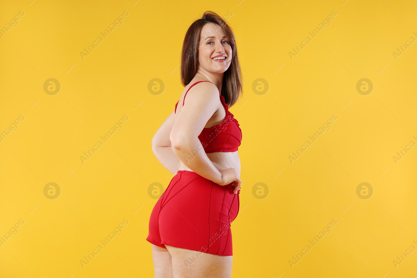 Photo of Woman in red underwear on orange background. Cellulite problem