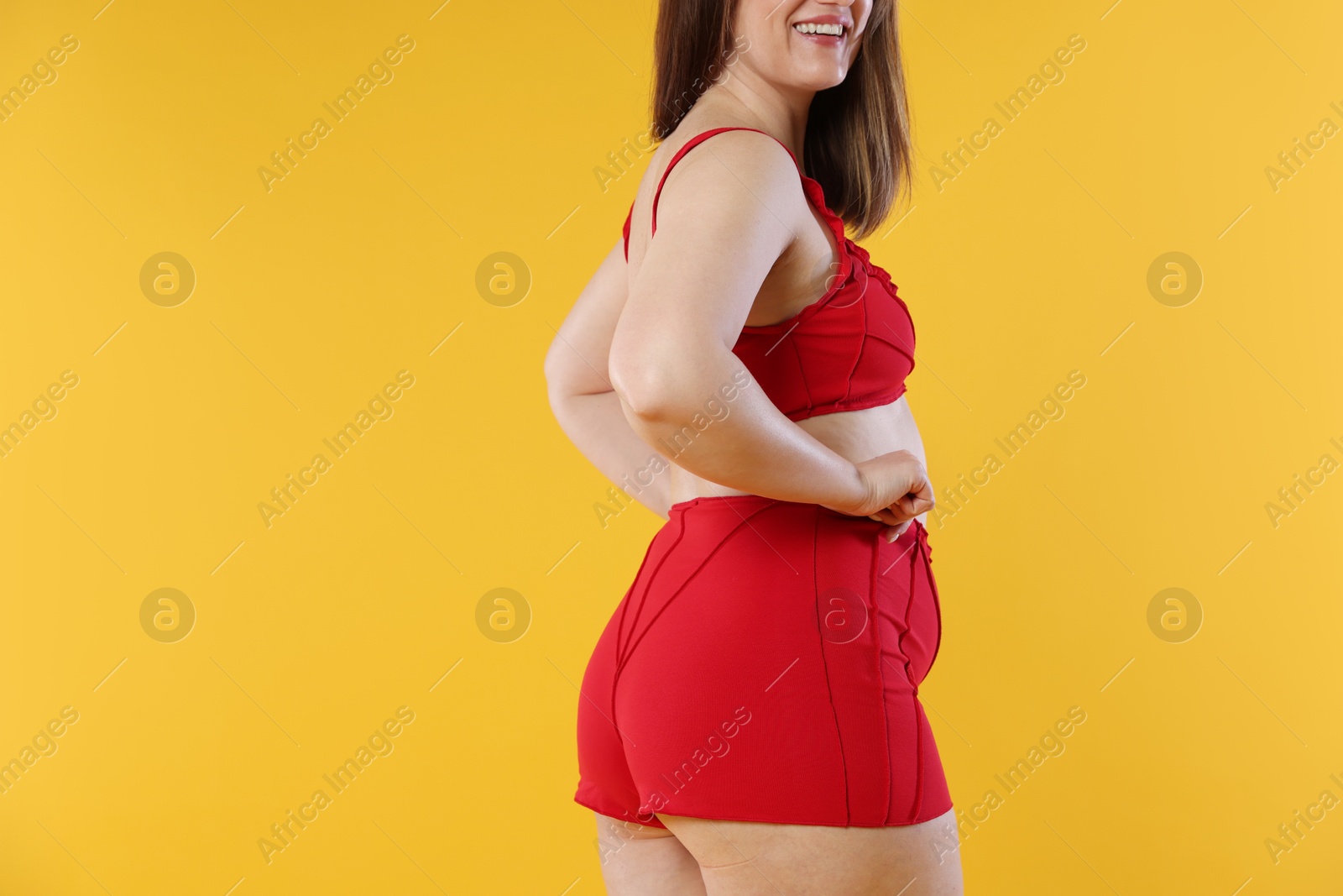 Photo of Woman in red underwear on orange background, closeup. Cellulite problem