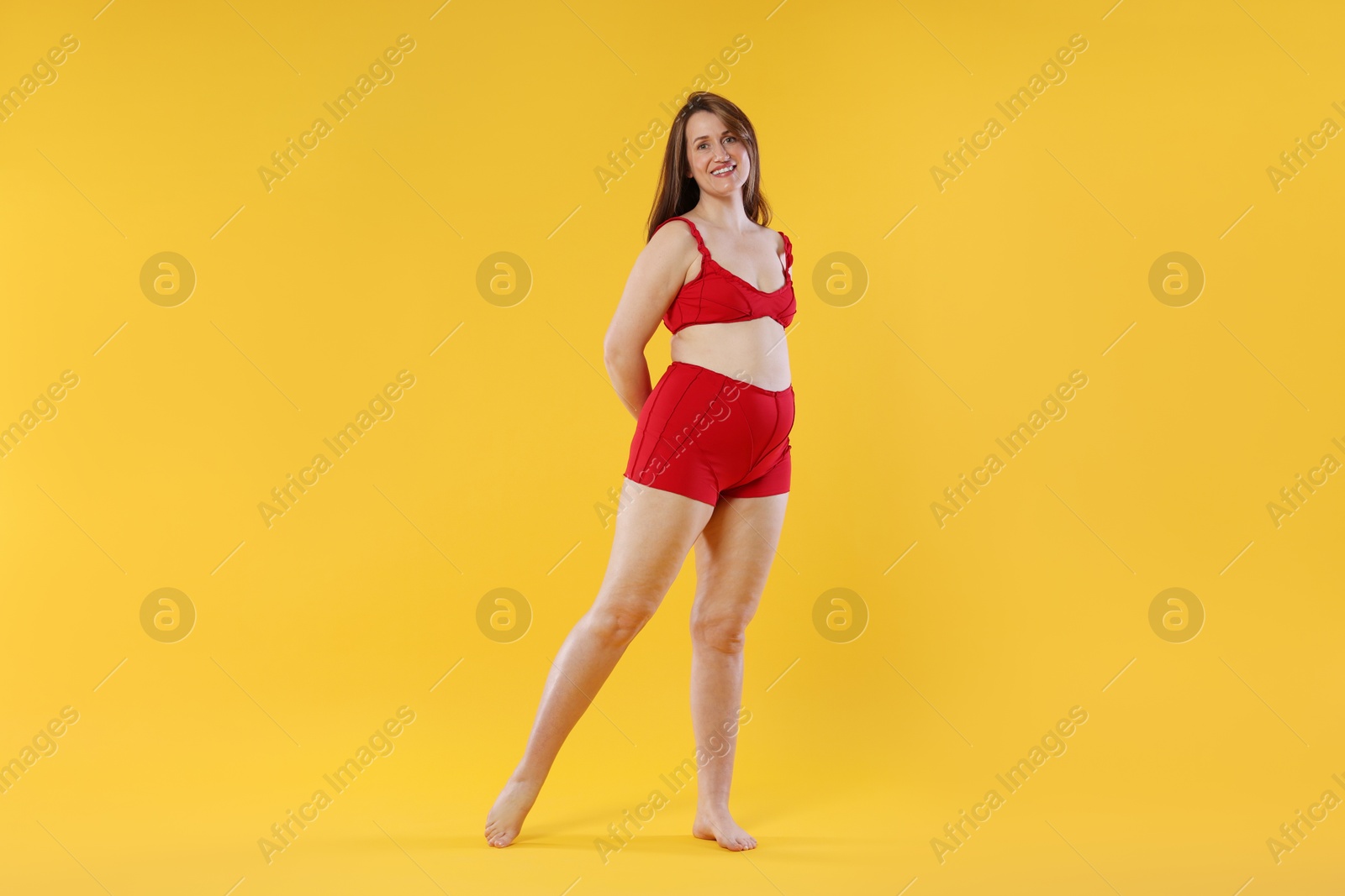 Photo of Woman in red underwear on orange background. Cellulite problem