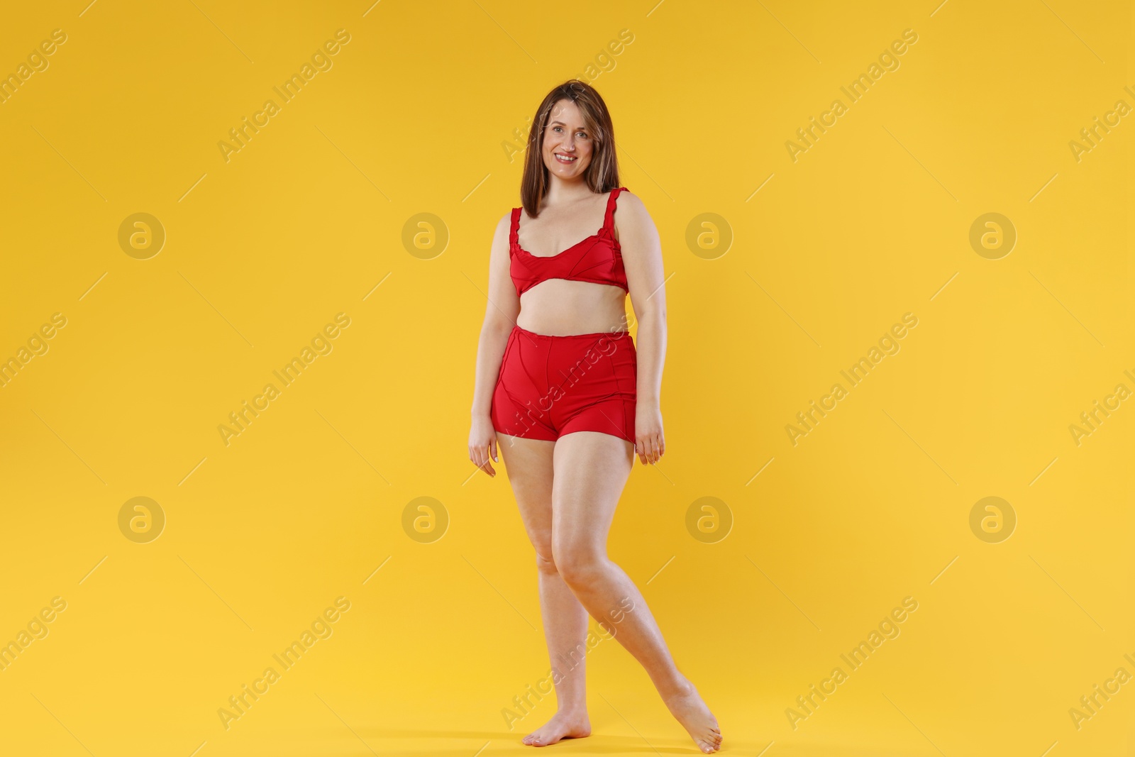 Photo of Woman in red underwear on orange background. Cellulite problem