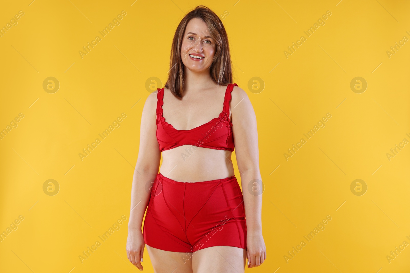 Photo of Woman in red underwear on orange background. Cellulite problem