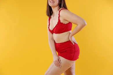 Photo of Woman in red underwear on orange background, closeup. Cellulite problem