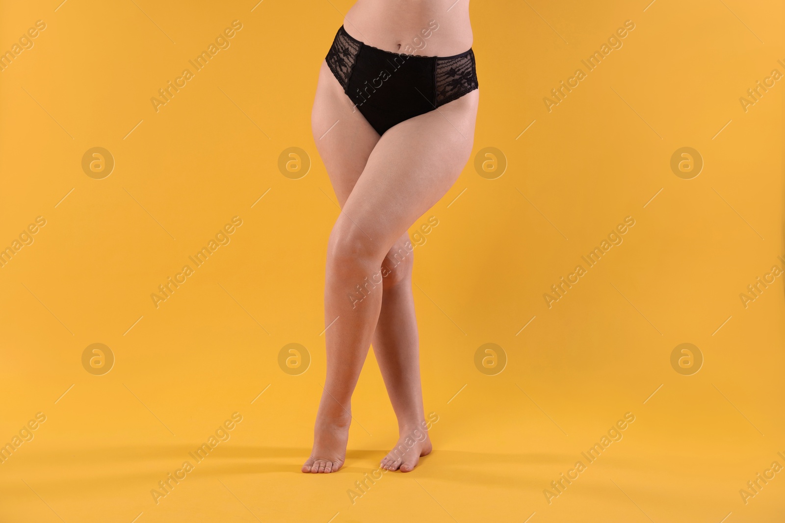 Photo of Woman in underwear on orange background, closeup. Cellulite problem