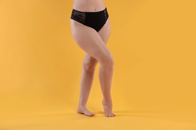 Photo of Woman in underwear on orange background, closeup. Cellulite problem