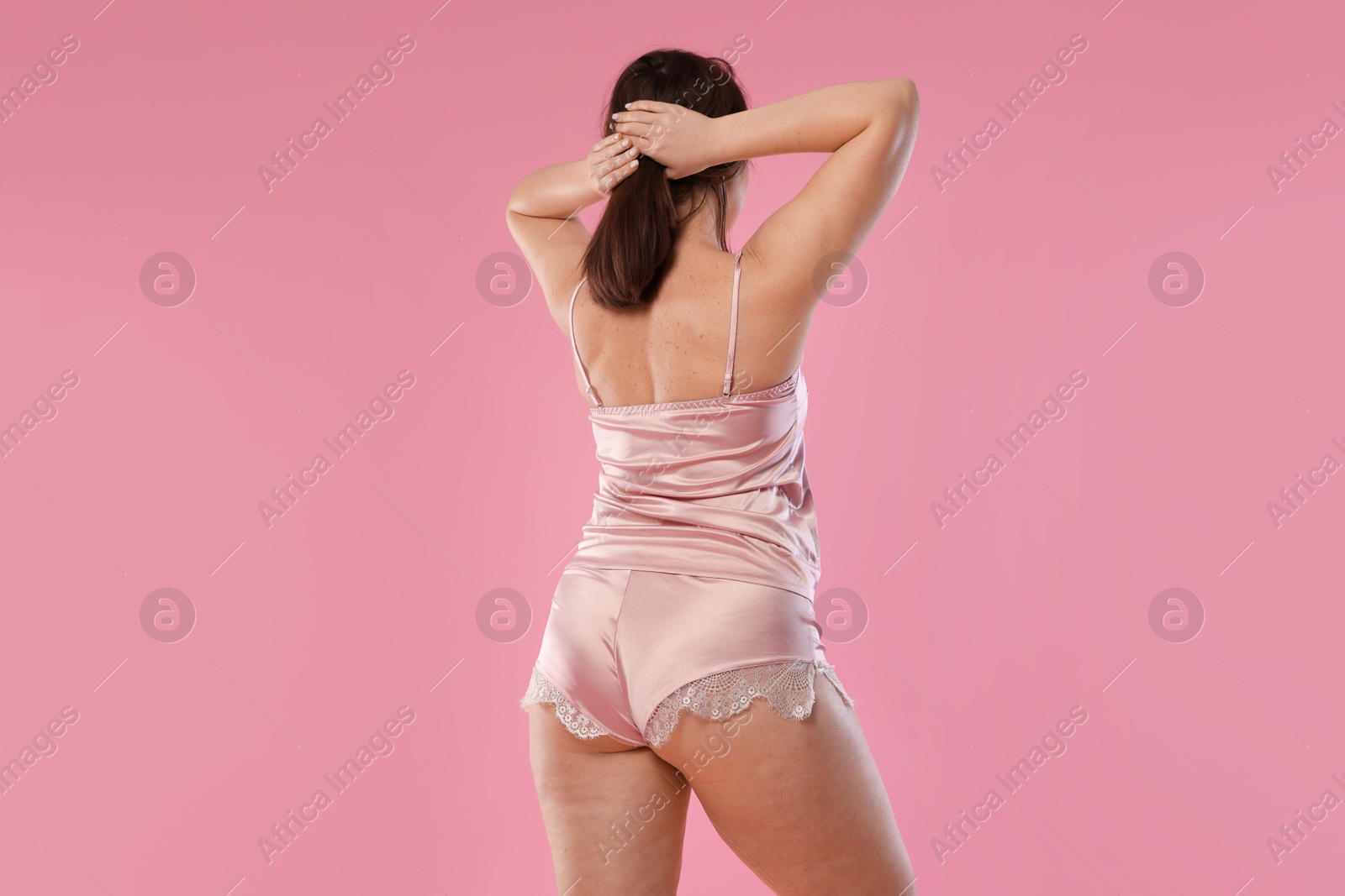 Photo of Woman in underwear on pink background, back view. Cellulite problem