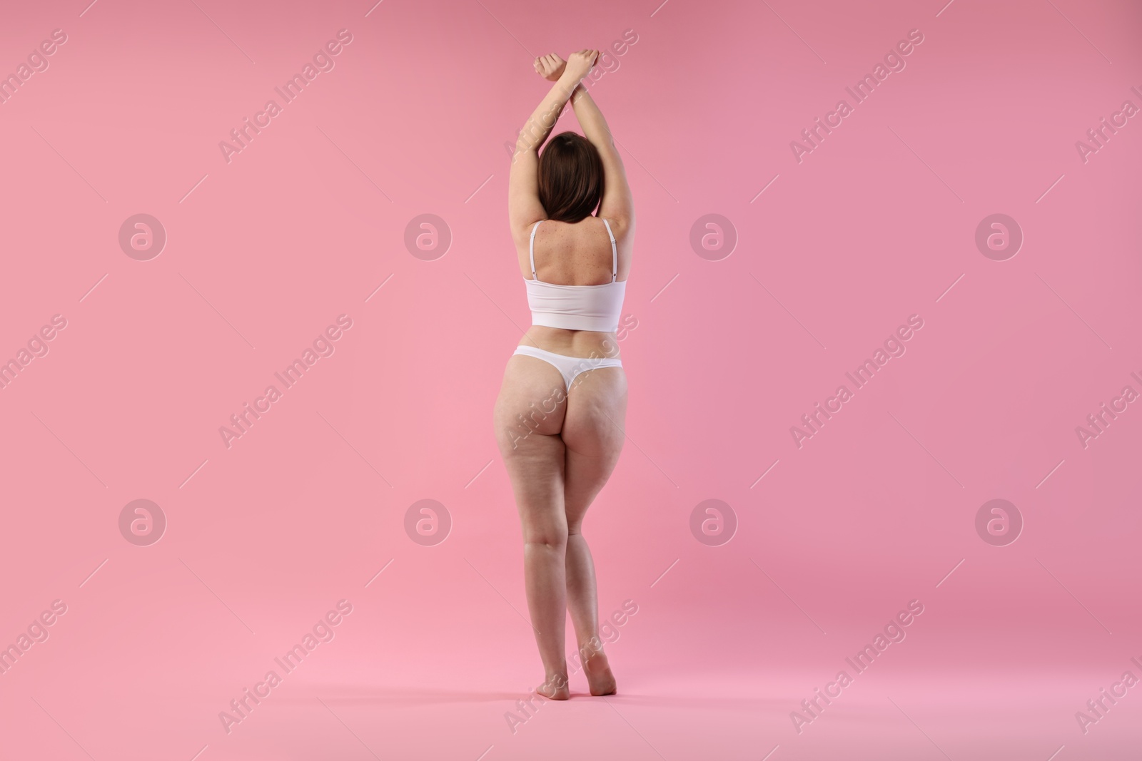 Photo of Woman in underwear on pink background, back view. Cellulite problem