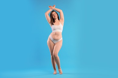 Photo of Woman in underwear on light blue background. Cellulite problem