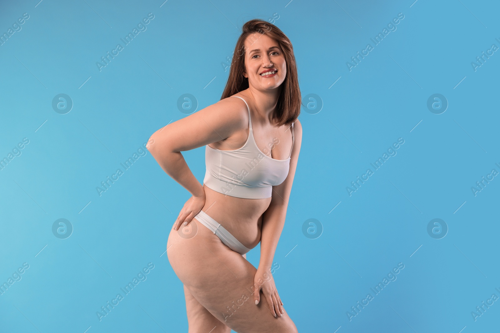 Photo of Woman in underwear on light blue background. Cellulite problem