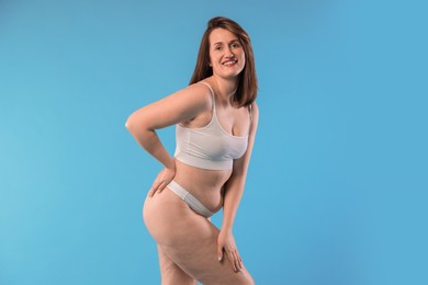 Woman in underwear on light blue background. Cellulite problem