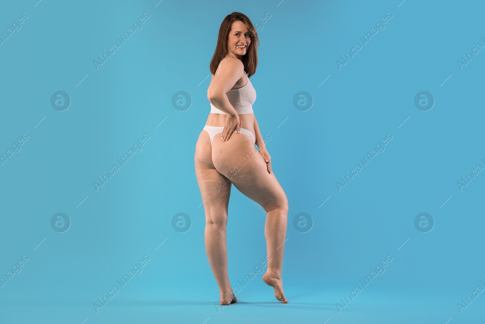 Photo of Woman in underwear on light blue background. Cellulite problem