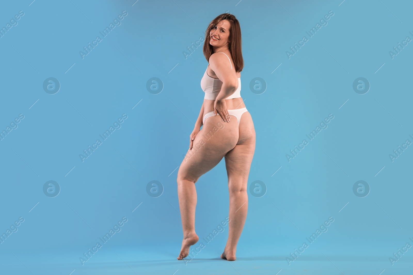 Photo of Woman in underwear on light blue background. Cellulite problem