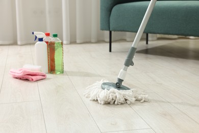 Photo of String mop, cleaning products and supplies on floor indoors