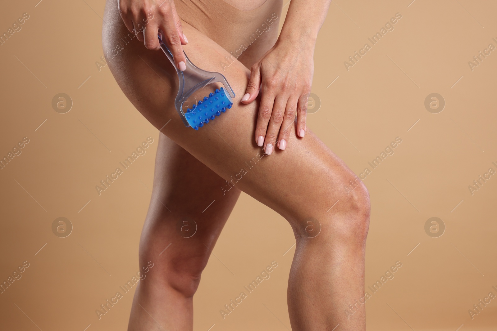 Photo of Woman doing anti cellulite massage with roller on beige background, closeup