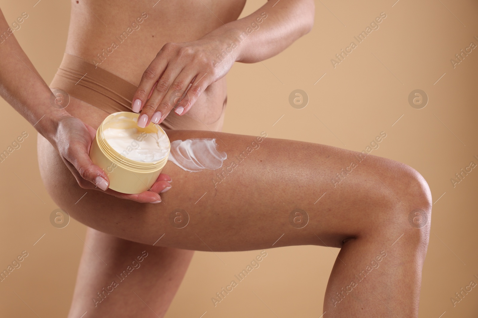 Photo of Woman applying anti cellulite cream on beige background, closeup