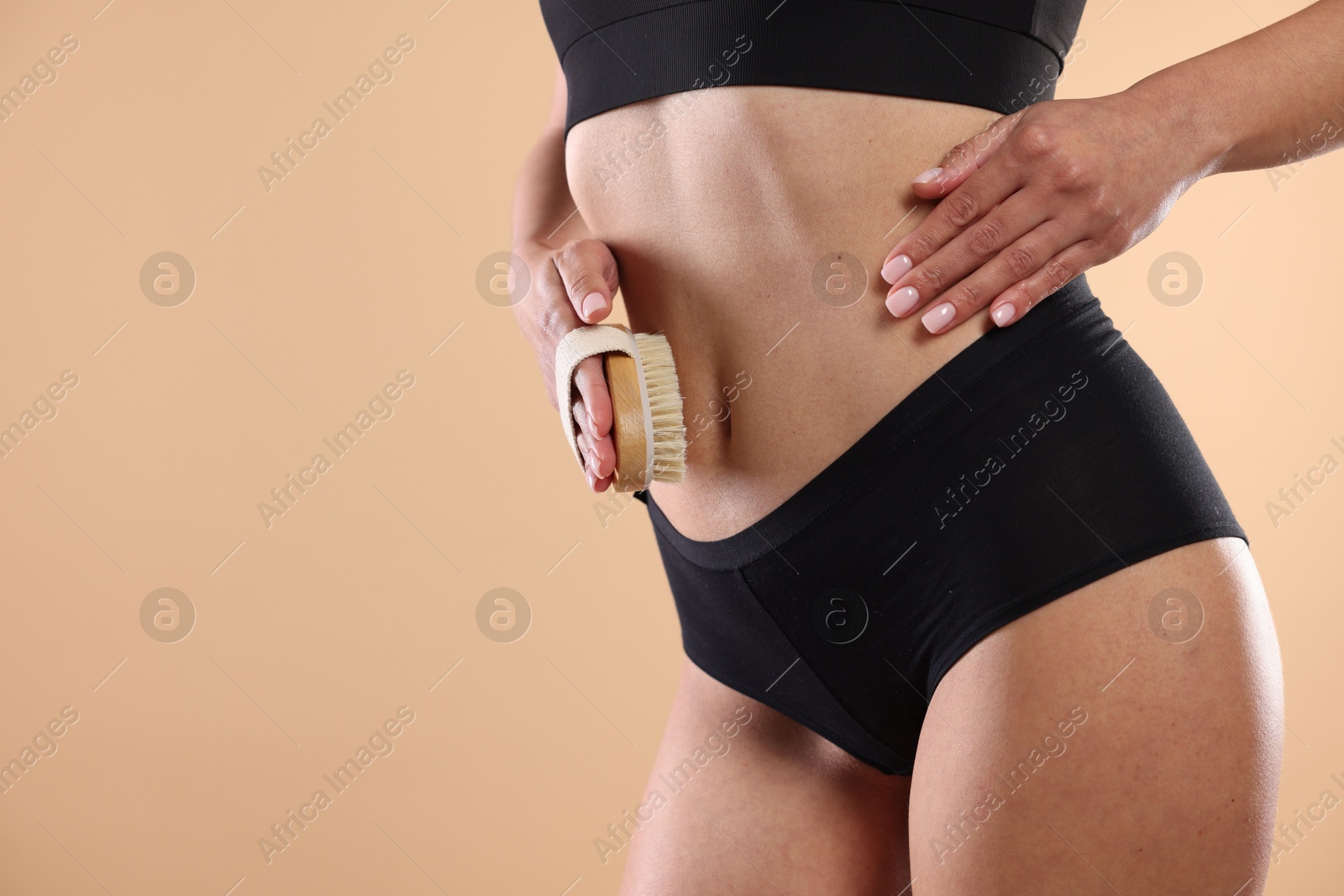 Photo of Woman doing anti cellulite massage with brush on beige background, closeup. Space for text