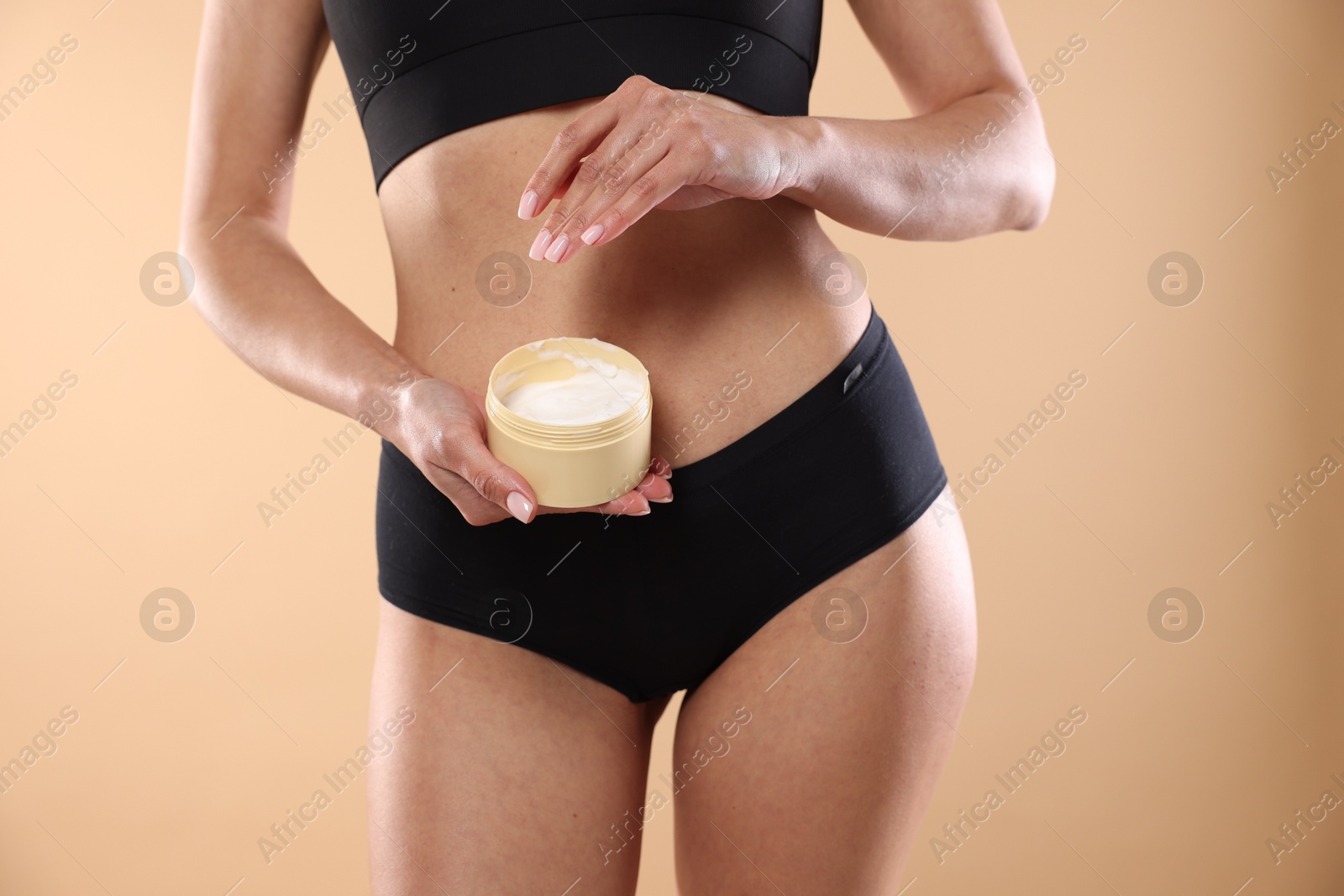 Photo of Woman applying anti cellulite cream on beige background, closeup