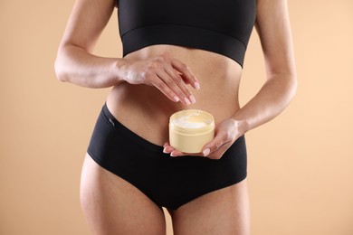 Photo of Woman applying anti cellulite cream on beige background, closeup