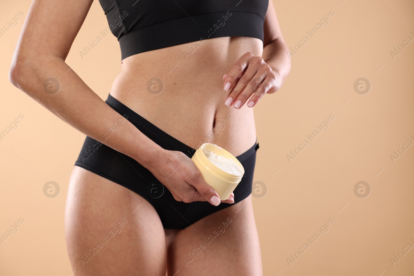 Photo of Woman applying anti cellulite cream on beige background, closeup