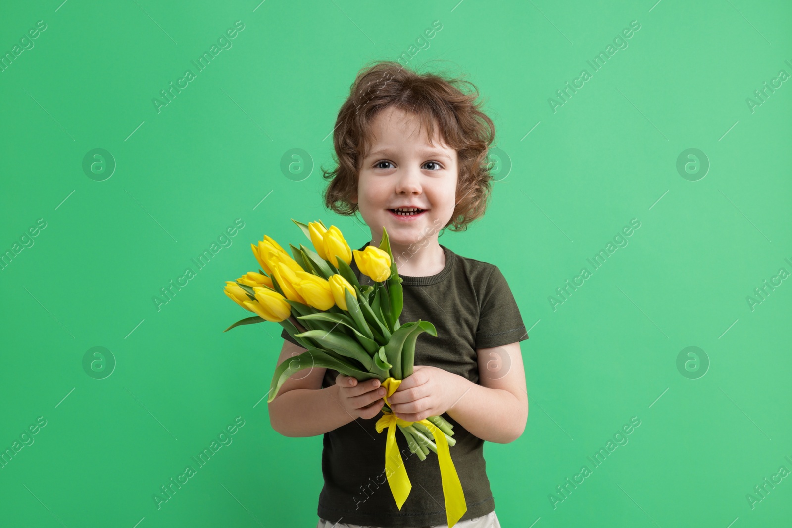 Photo of Cute little boy with bouquet of tulips on green background