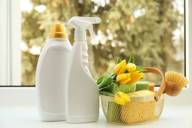 Photo of Spring cleaning. Detergents, supplies and tulips on windowsill indoors