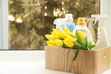 Photo of Spring cleaning. Detergents, supplies and tulips on windowsill indoors, space for text