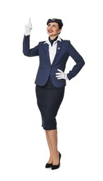 Smiling stewardess pointing upwards on white background