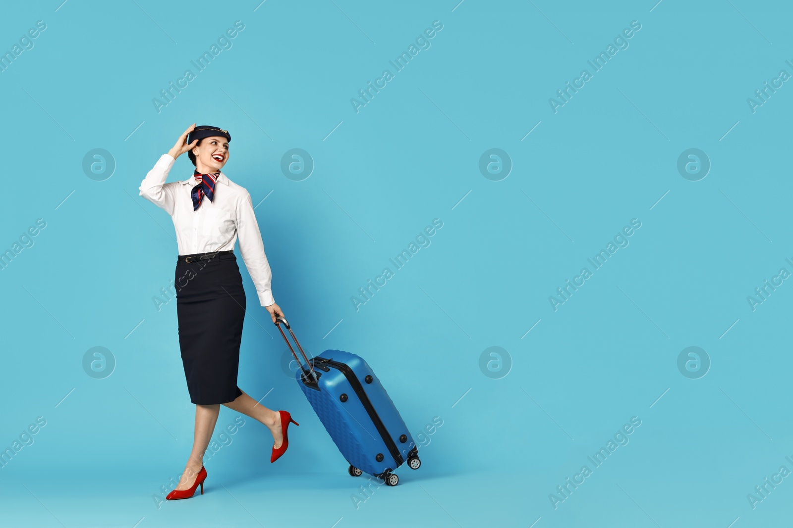 Photo of Happy flight attendant with suitcase on light blue background. Space for text