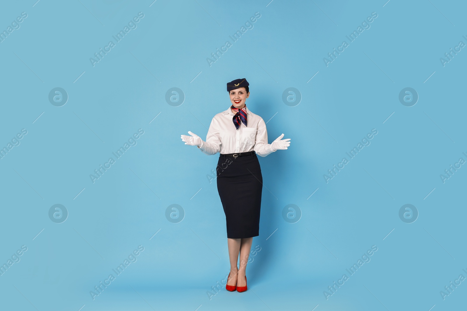 Photo of Smiling flight attendant demonstrating safety instruction on light blue background