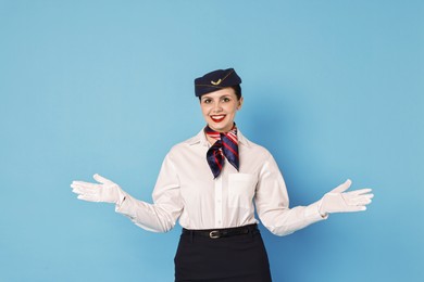 Photo of Smiling flight attendant demonstrating safety instruction on light blue background