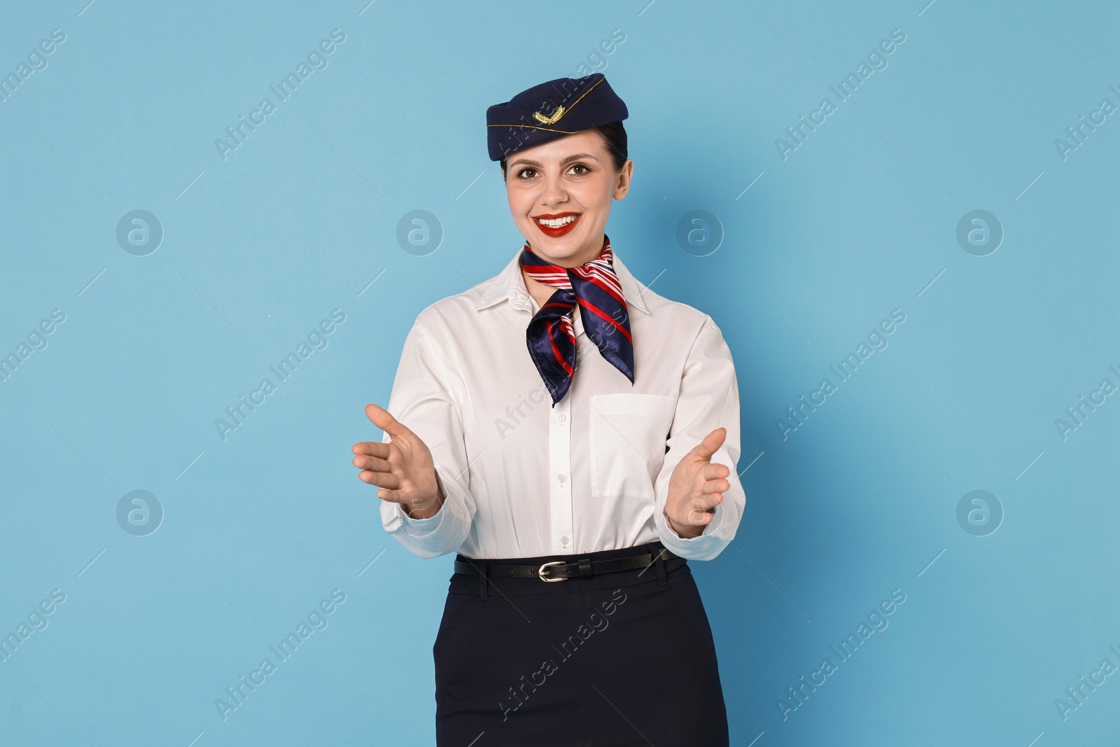 Photo of Smiling flight attendant demonstrating safety instruction on light blue background