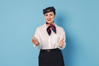 Photo of Smiling flight attendant demonstrating safety instruction on light blue background