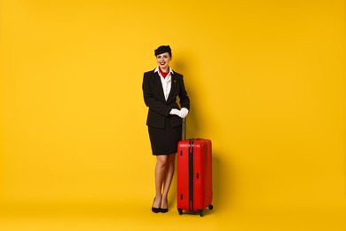 Happy flight attendant with suitcase on orange background