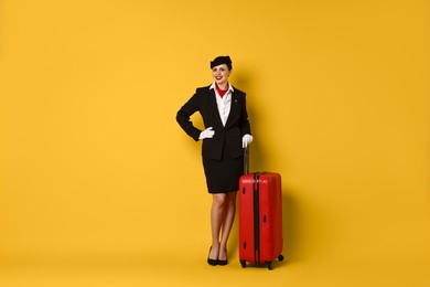 Happy flight attendant with suitcase on orange background