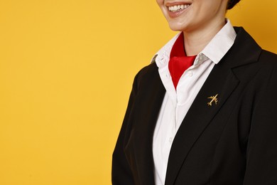 Happy flight attendant on yellow background, closeup. Space for text