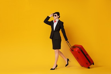 Photo of Happy flight attendant with suitcase on orange background. Space for text