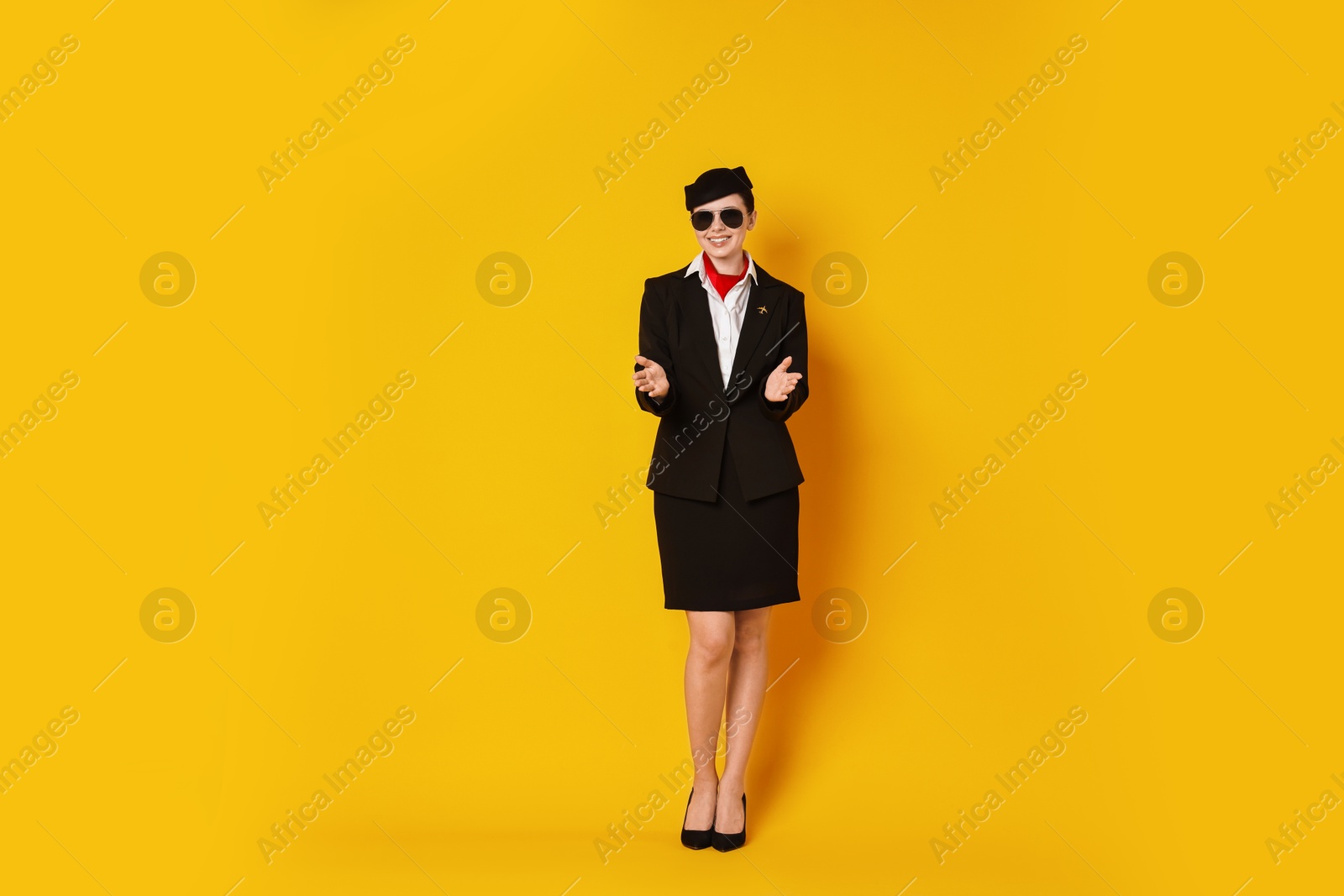 Photo of Smiling flight attendant demonstrating safety instruction on orange background