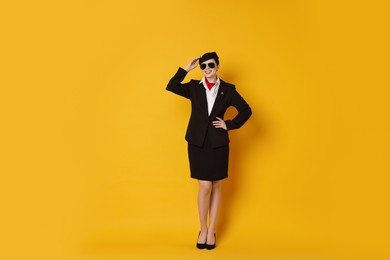 Happy flight attendant in sunglasses on orange background